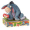Jim Shore Disney Traditions Eeyore figurine holding a red heart on a patterned base.
