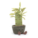 A plush bamboo plant with five green linen stems, red-brown stitches, suede-like leaves, sitting in a suede pot with fluffy soil. It has corded feet and a cheerful face.
