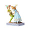 Colorful figurine depicting Peter Pan in green attire facing Wendy in a blue dress with Tinker Bell above them, from the Jim Shore Disney Traditions collection.