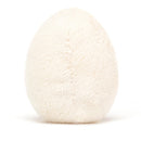 Soft plush toy resembling a boiled egg with fluffy white exterior, bright yellow centre, and playful cord-like feet