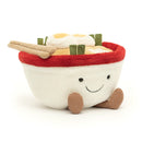 A plush toy representing a bowl of ramen, complete with textured noodles, spring onions, boiled eggs, and a pink fish cake. 