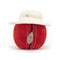 A plush toy resembling a red cricket ball with detailed stitching, wearing a white sunhat.