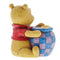 Rear view of the Jim Shore Disney Traditions collectible figurine, showing Mini Winnie the Pooh in a red shirt embracing a colorful honey pot with quilt-like patterns.