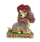 Disney Traditions Lady Christmas has a striking blue patterned coat, and wears a charming red flower wreath 